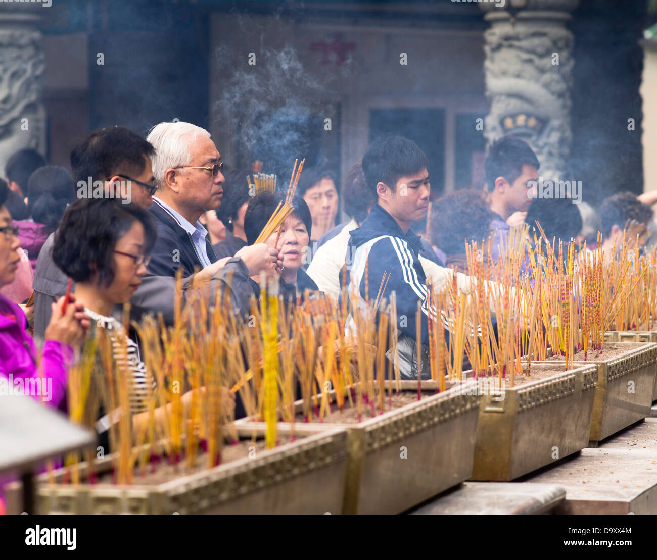 dh Wong Tai Sin Temple WONG TAI SIN HONG KONG Cina adoratori joss bastoni tempio santuario cinese persone joss bastone urns culto taoista Foto Stock