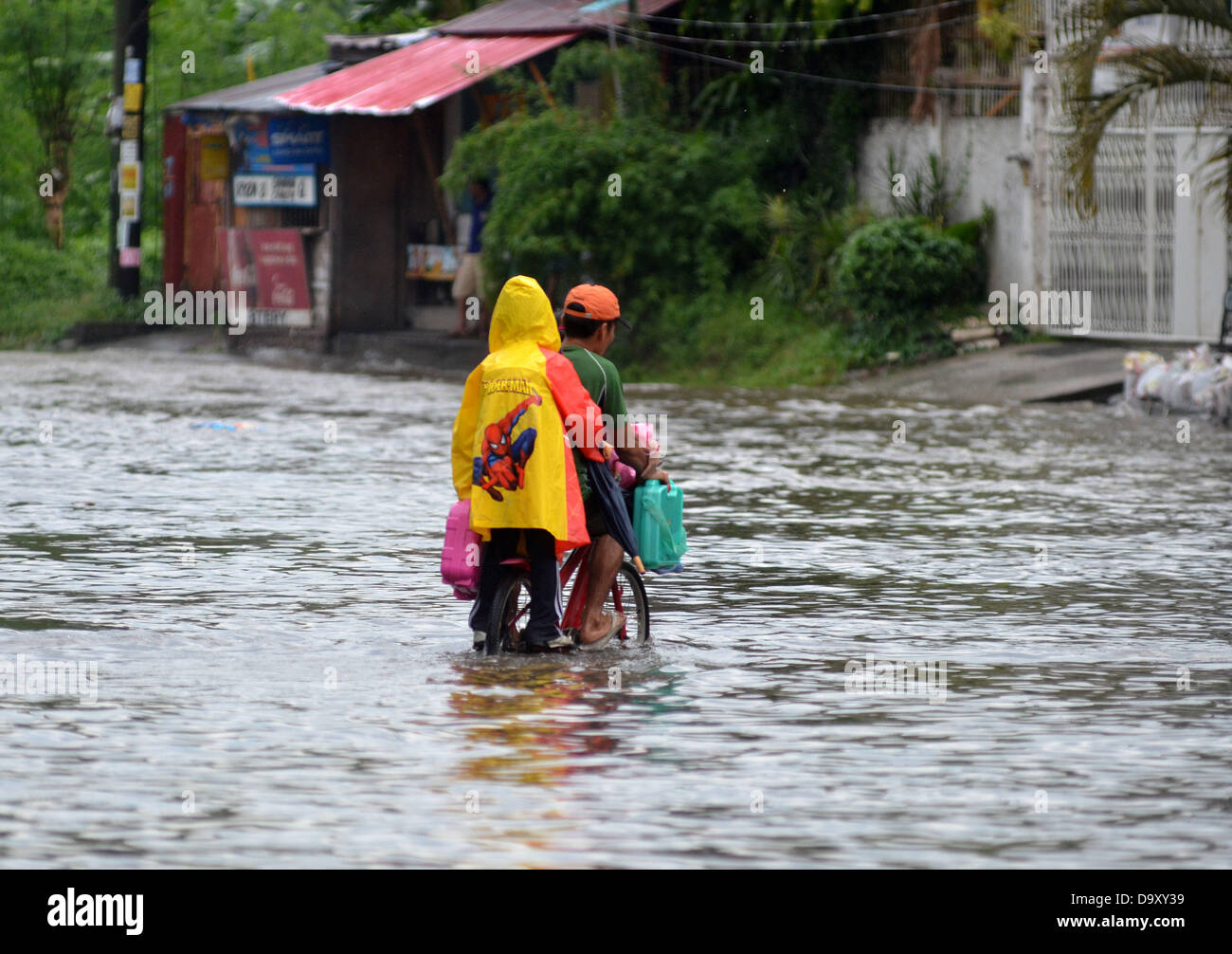 Davao, Philipinnes. Il 28 giugno 2013. Residenti filippini manovre come provano a passare in una strada allagata causa da un pesante acquazzone di pioggia a Davao City, nel Sud delle Filippine, 28 giugno 2013. Secondo Philippine atmosferica e geofisici Astronomical Services Administration (PAGASA), segnale di tempesta numero uno è sollevata in aree di Visayas e Mindanao come depressione tropicale 'Gorio' entra in territorio filippino. Credito: Eli Ritchie Tongo/Alamy Live News Foto Stock