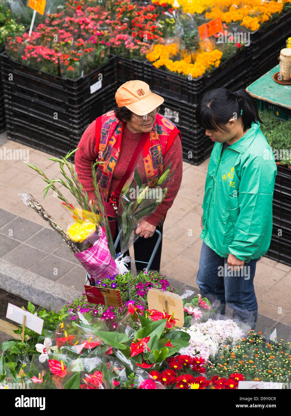 dh mercato dei fiori MONG KOK HONG KONG Donna che acquista fiori in bancarella dei fiori anziani cinesi mongkok persone Foto Stock