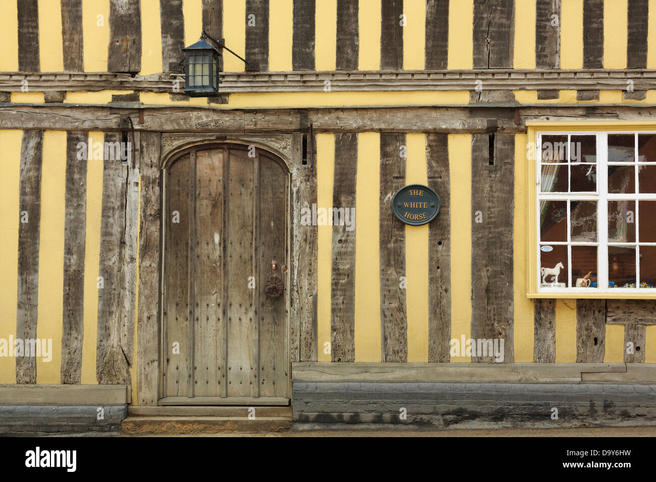 Vecchia porta di legno nel xv secolo giallo edificio con travi di legno in precedenza il White Horse Inn a Lavenham, Suffolk, Inghilterra, Regno Unito, Gran Bretagna Foto Stock