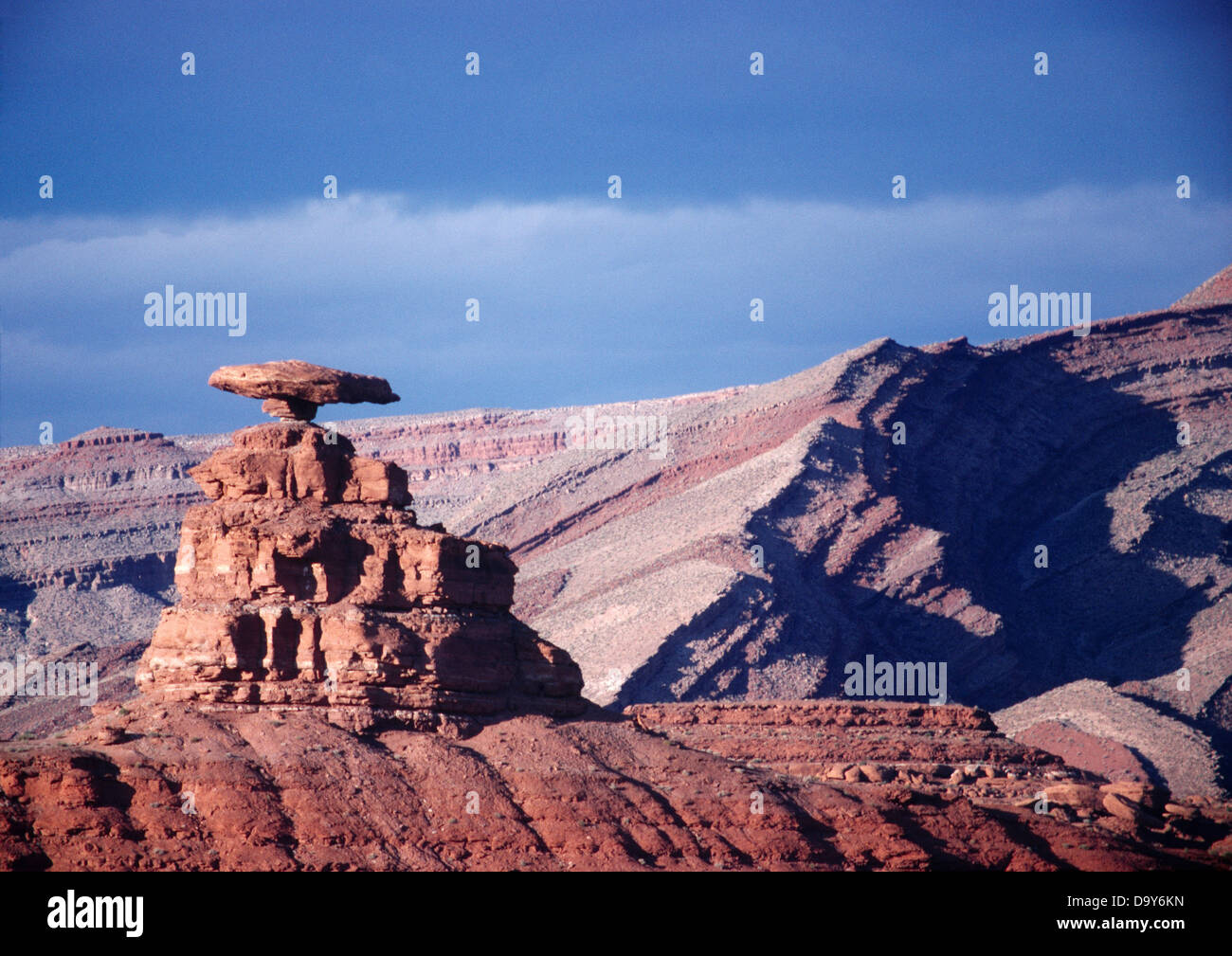 Mexican Hat rock bilanciato resistente alla erosione formazione Halgaito arenaria con il crest Raplee piega anticlinale al di là di Mexican Hat Utah. Foto Stock