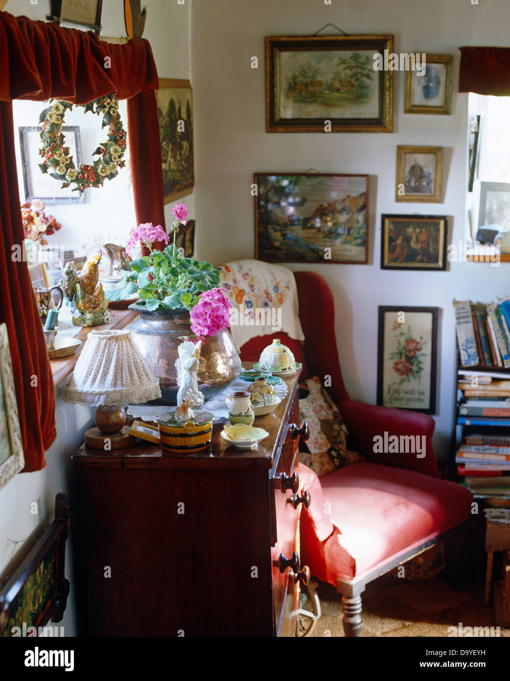 Vecchio torace-di-cassetti e poltrona vittoriana in angolo del cottage ingombra la stanza di seduta con il gruppo di foto sulla parete Foto Stock