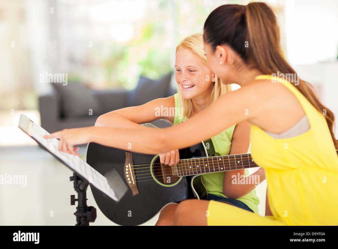 Giovane ragazza preteen avente lezione di chitarra a casa Foto Stock