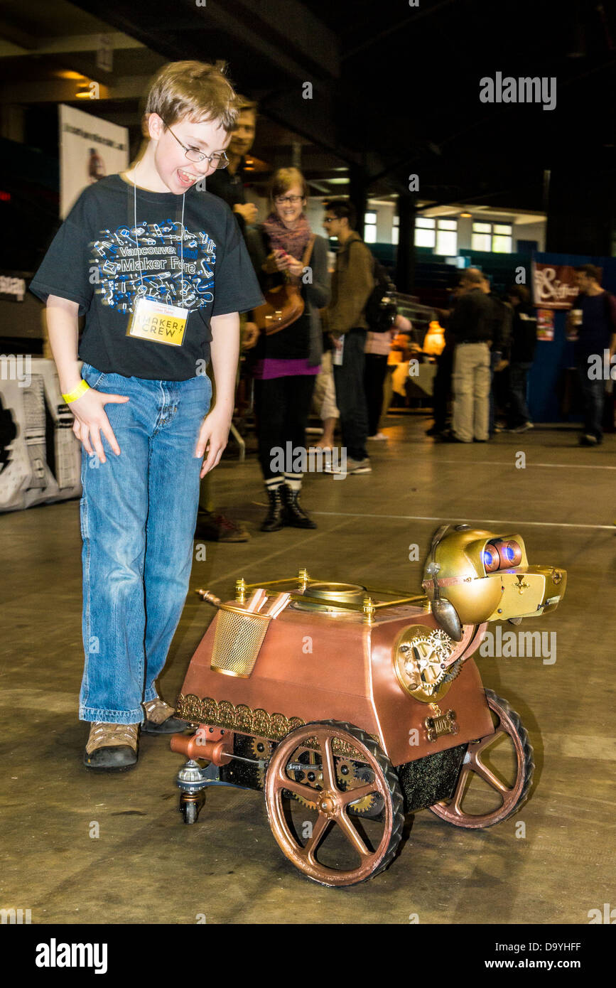 Ragazzo è affascinare da cane robotico presso il Vancouver Mini Maker Faire. Foto Stock