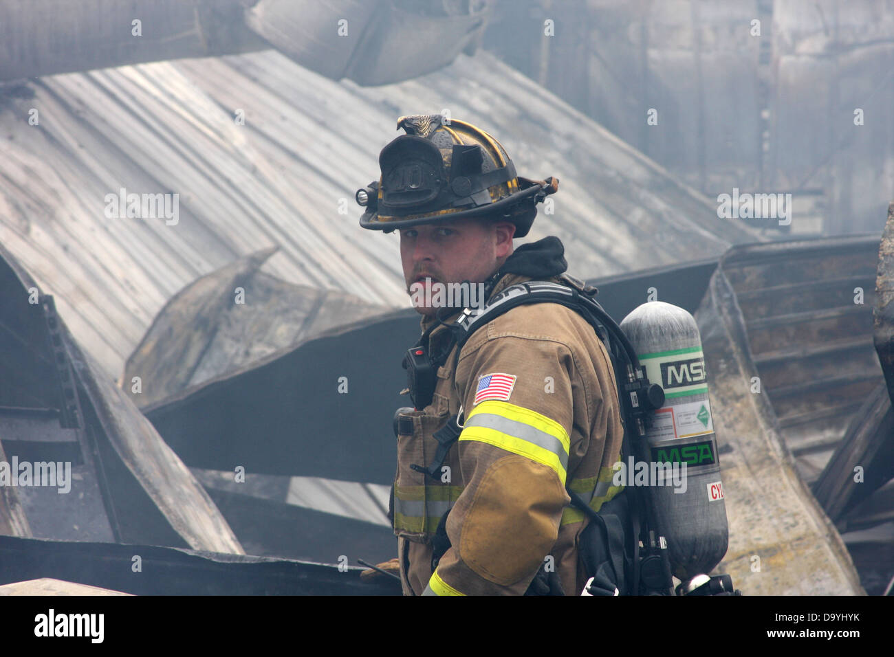 Un vigile del fuoco di scavare attraverso i detriti da una forma ripiegata bruciato edificio da un incendio Foto Stock