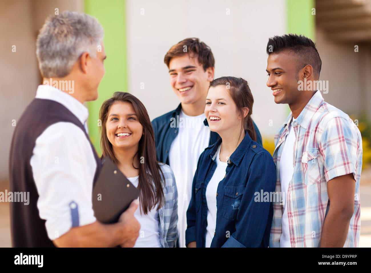 Persone di mezza età insegnante di scuola superiore a parlare con gli studenti durante la pausa Foto Stock