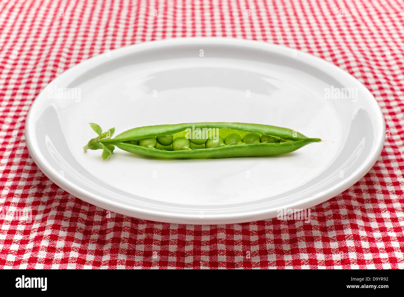 Materie piselli sul piatto di portata in ceramica bianca servita sul tavolo da cucina. Dietologia e mangiare sano concetto. Foto Stock