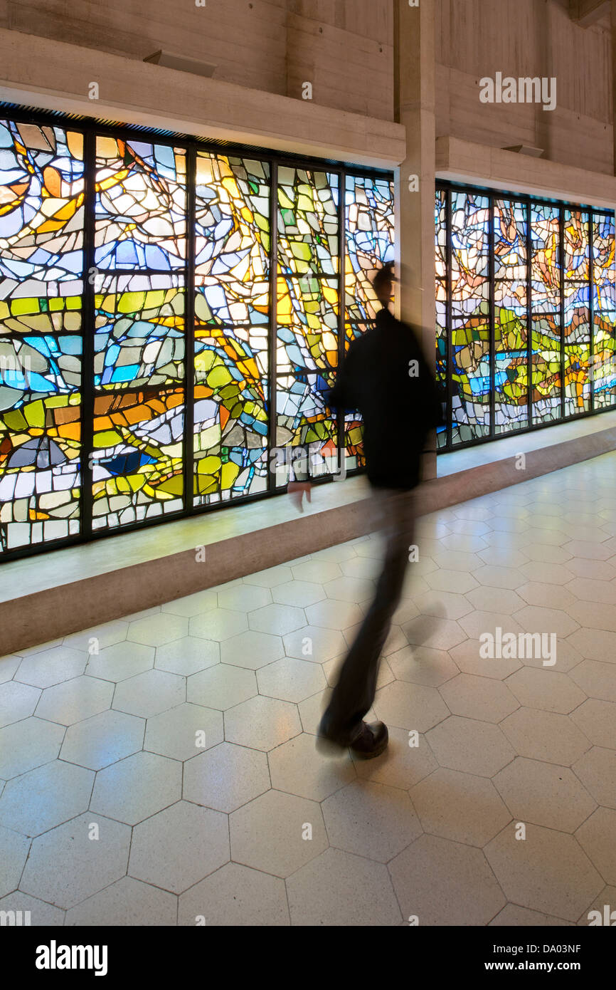 Un uomo che cammina davanti ad una finestra di vetro colorato all'interno della Cattedrale di Clifton, Bristol, Regno Unito. Foto Stock