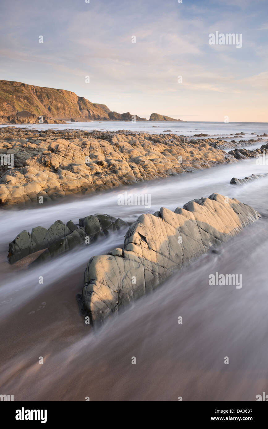 Luce della Sera hits rocce sulla bocca Welcombe Beach, North Devon, Regno Unito. Foto Stock