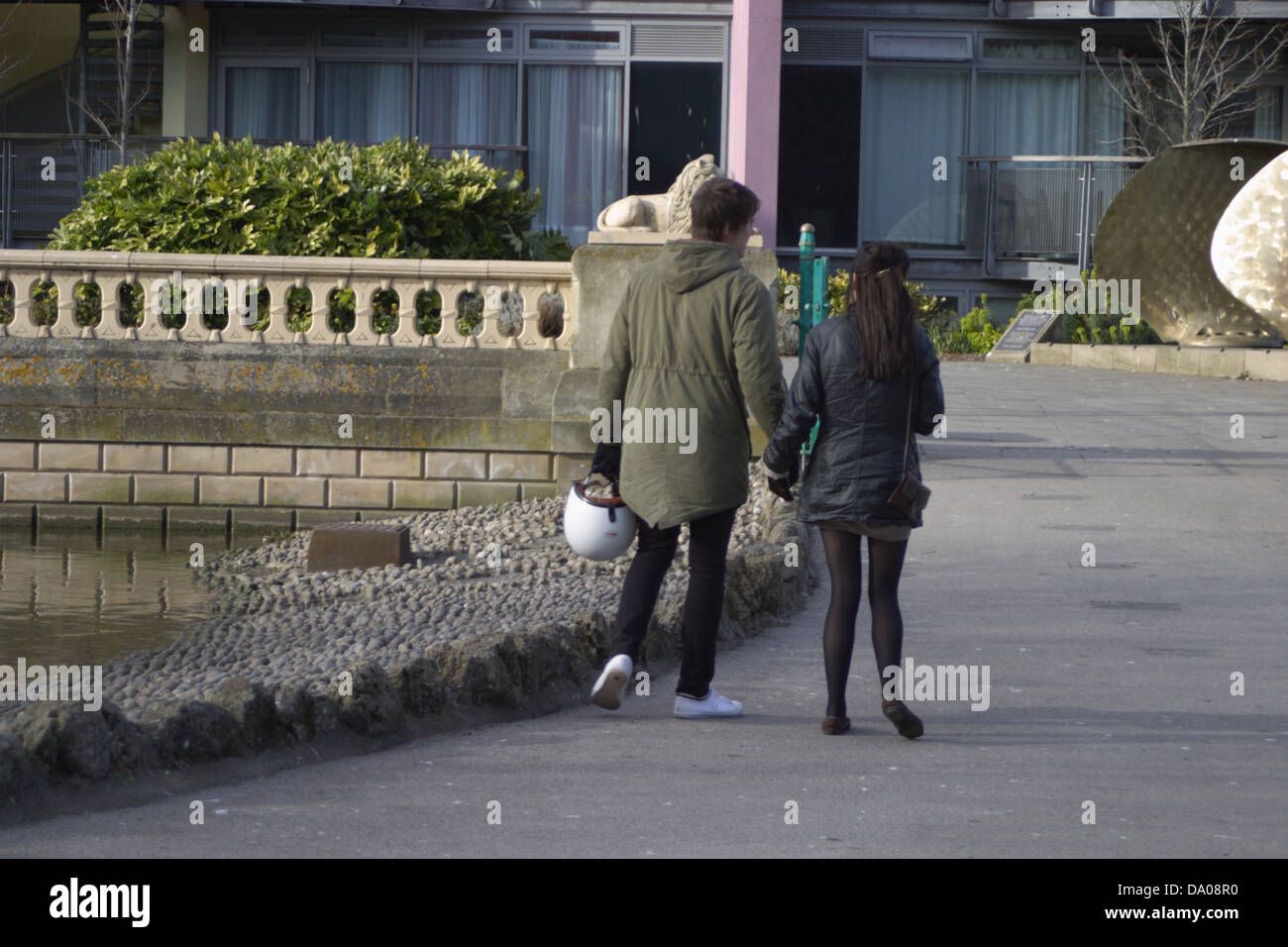 Un giovane Holding Hands, camminando attraverso mowbray park sunderland. L uomo e la donna nel parco. L'uomo ha un casco in mano. Foto Stock