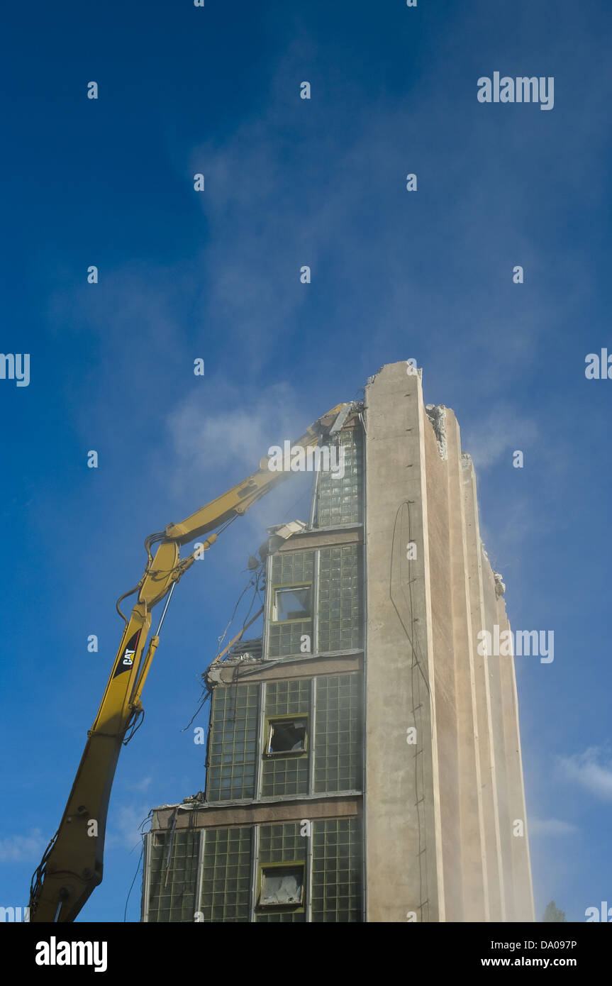 Grande giallo, escavatore bulldozer la demolizione di un edificio alto in una giornata di sole Foto Stock
