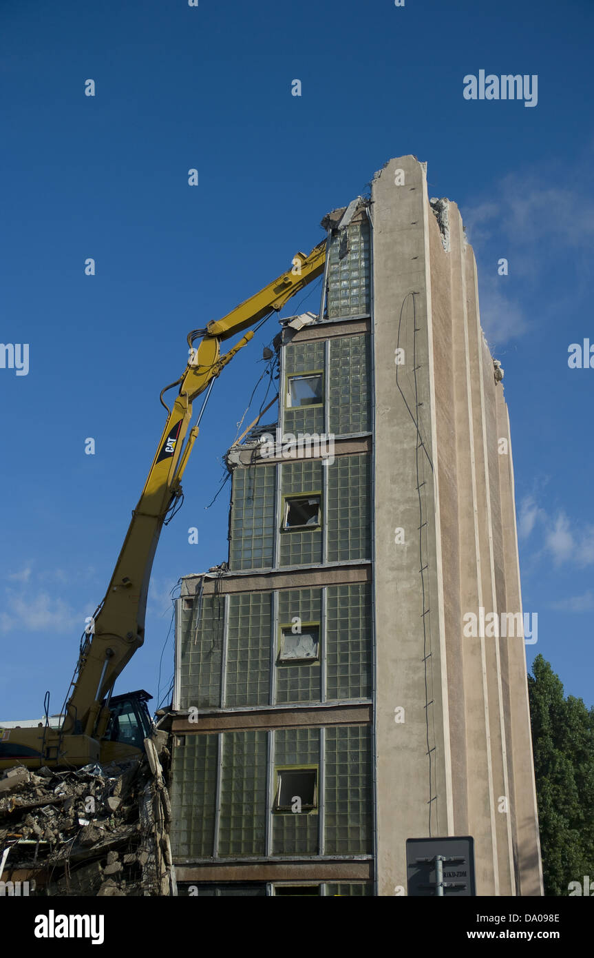 Grande giallo, escavatore bulldozer la demolizione di un edificio alto in una giornata di sole Foto Stock