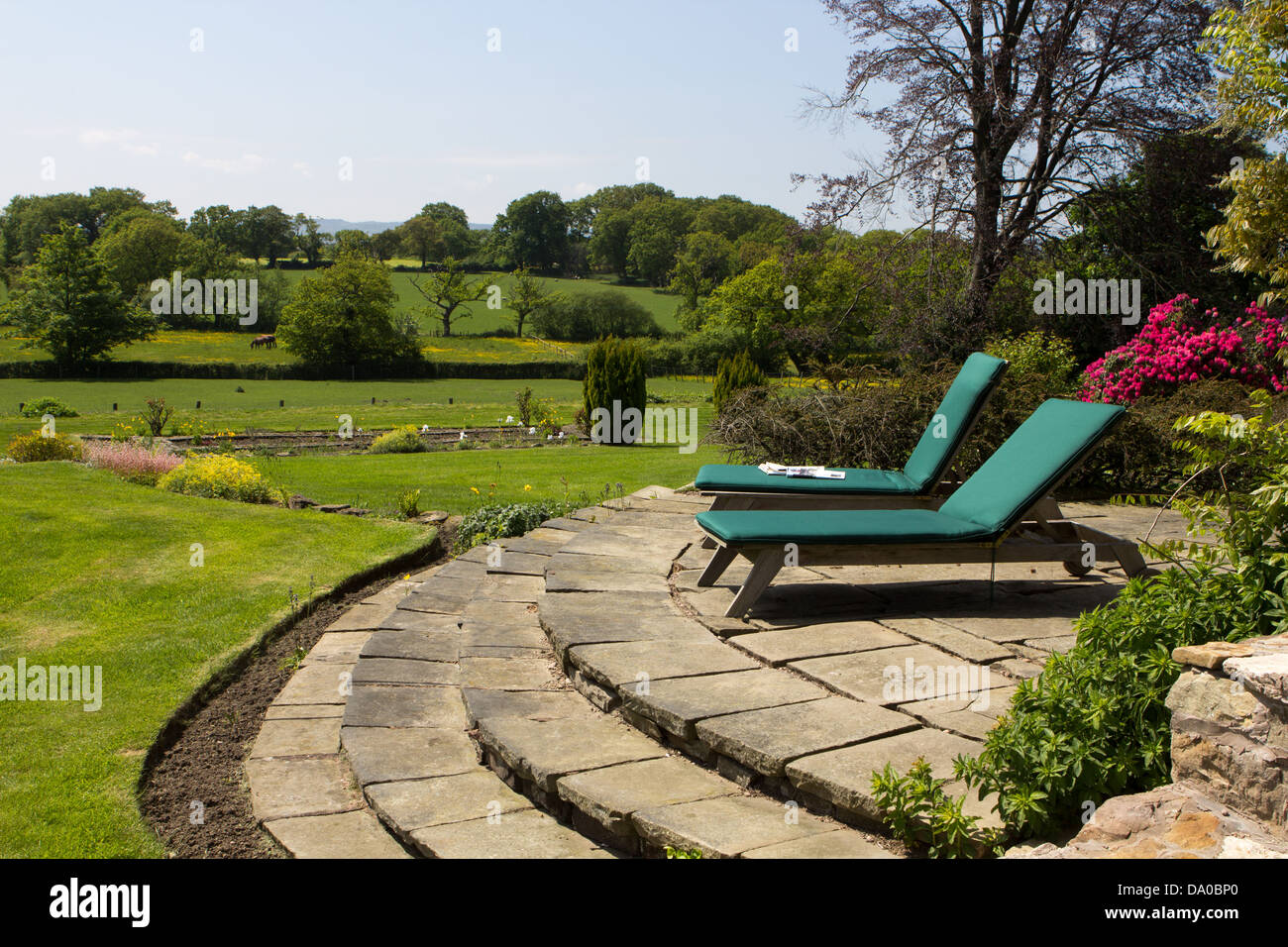Due sedie a sdraio su un patio si affacciano sulla campagna Gallese Foto Stock