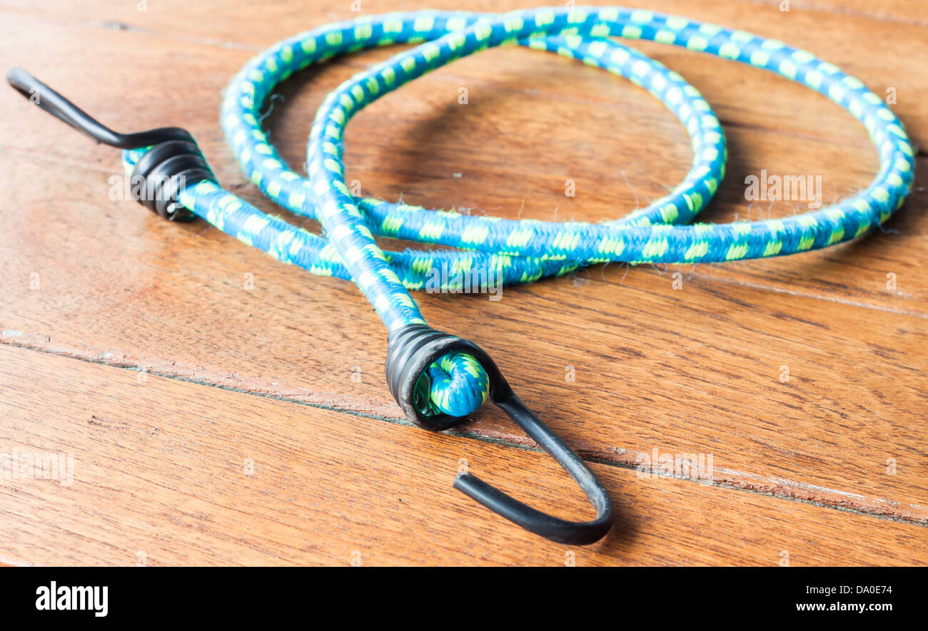 Blue corda elastica con ganci in metallo su uno sfondo di legno Foto Stock