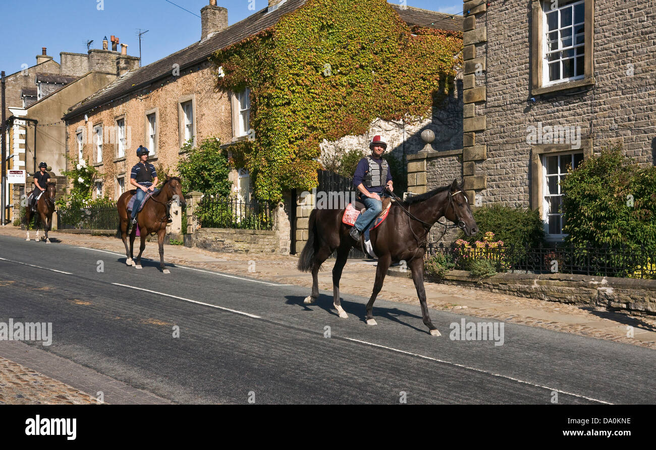 Ai cavalli da corsa essendo cavalcato attraverso Middleham, North Yorkshire, sulla strada del ritorno dalla formazione galoppa. Foto Stock