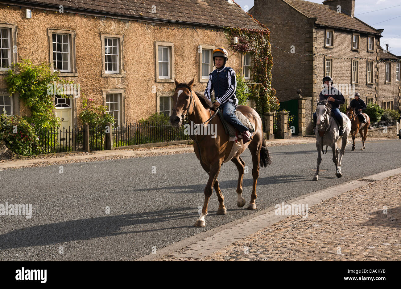 Ai cavalli da corsa essendo cavalcato attraverso Middleham, North Yorkshire, sul loro modo alla formazione galoppa. Foto Stock