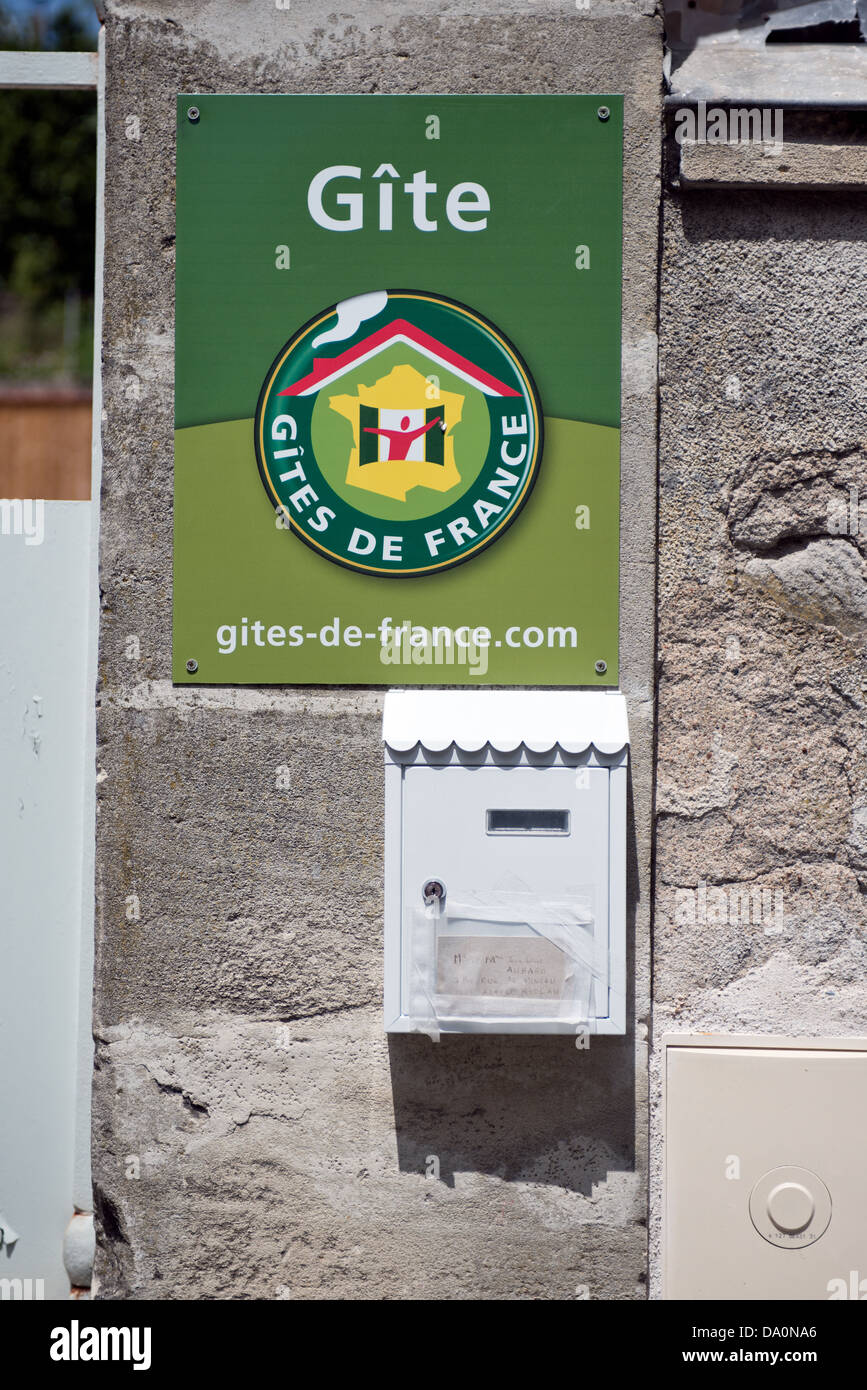 Un segno pubblicità gîte in affitto da Gites de France montato su una parete al di sopra di un tipico francese letterbox, Francia Foto Stock