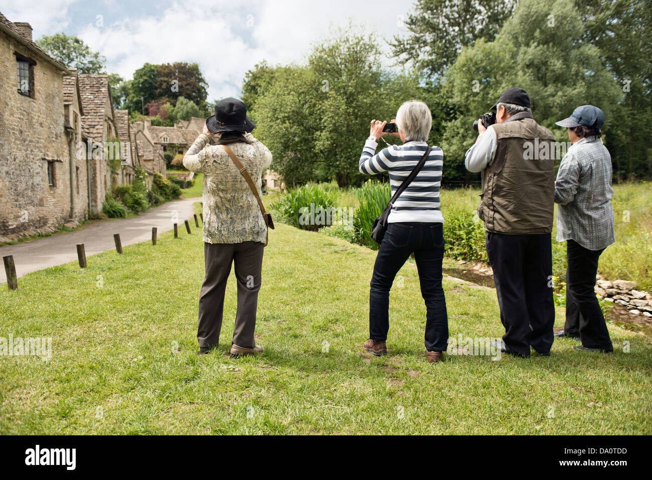 Turisti asiatici a scattare foto di Arlington Row a Bibury, Gloucestershire, Regno Unito Foto Stock