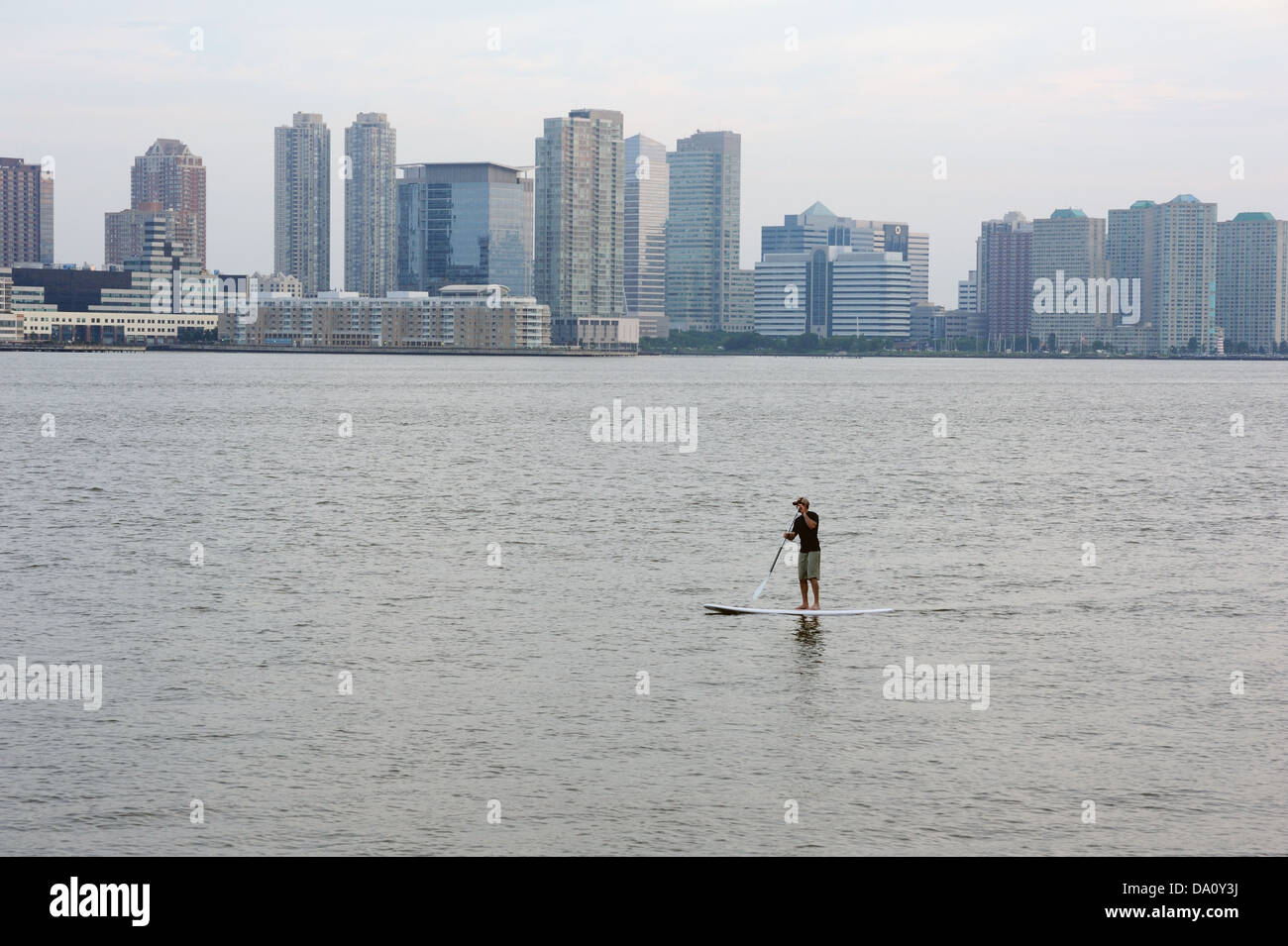 Un uomo di canoa sul fiume Hudson nel porto di New York. Jersey City è in background. Foto Stock