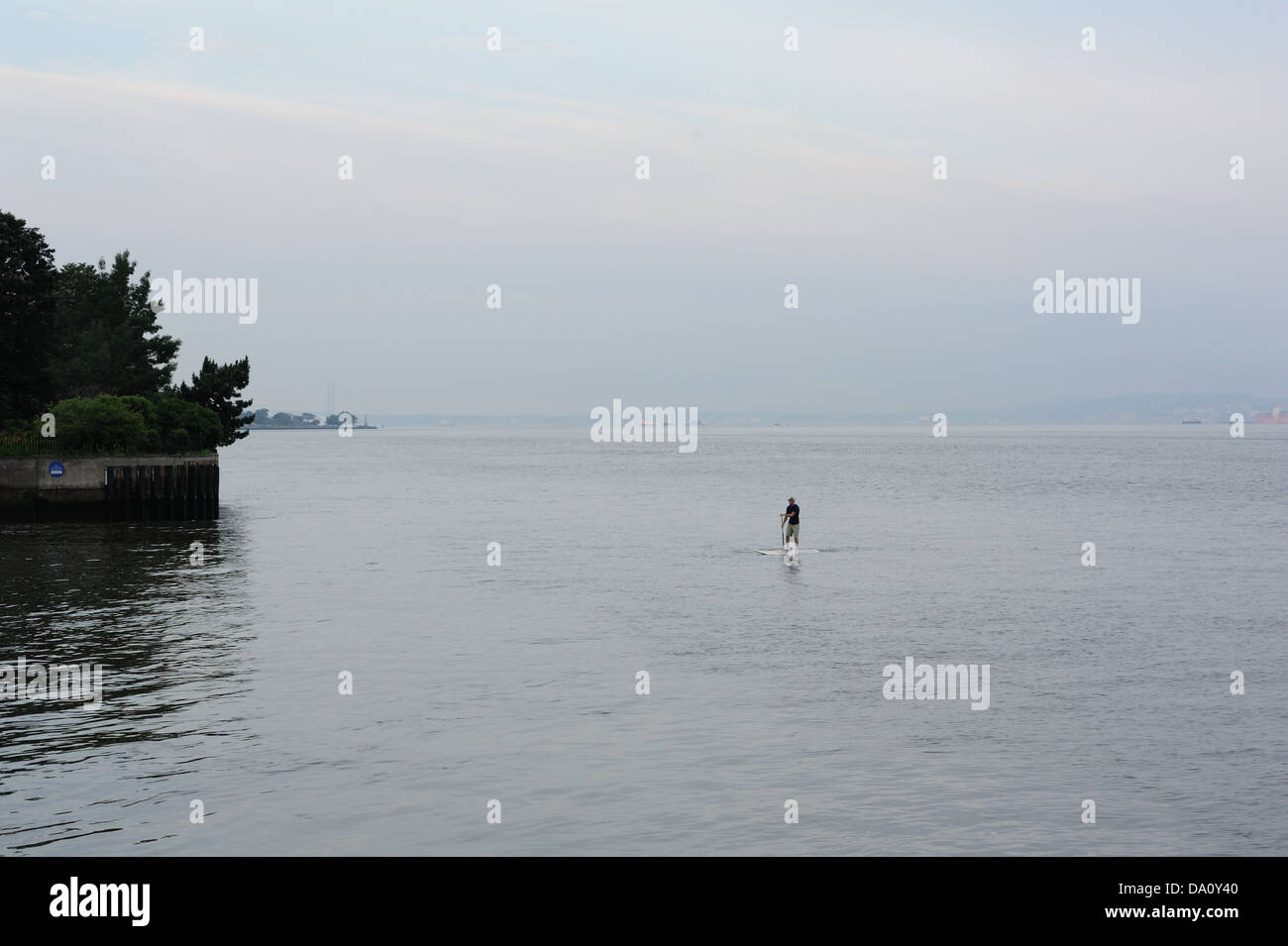 Un uomo stand-up paddling sul fiume Hudson nei pressi di Battery Park City in Lower Manhattan. Foto Stock