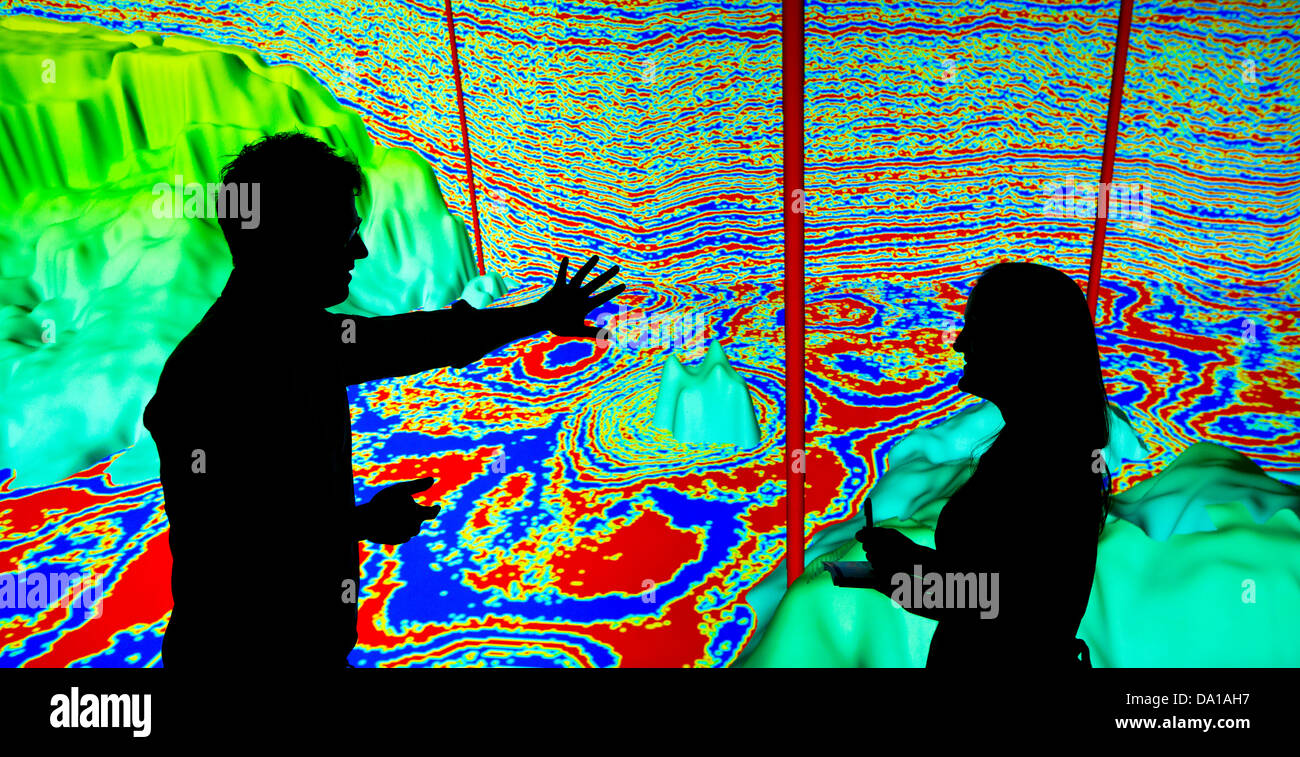 I geologi guardando un grafico sismico con strati di roccia e pozzi di petrolio visualizzati Foto Stock