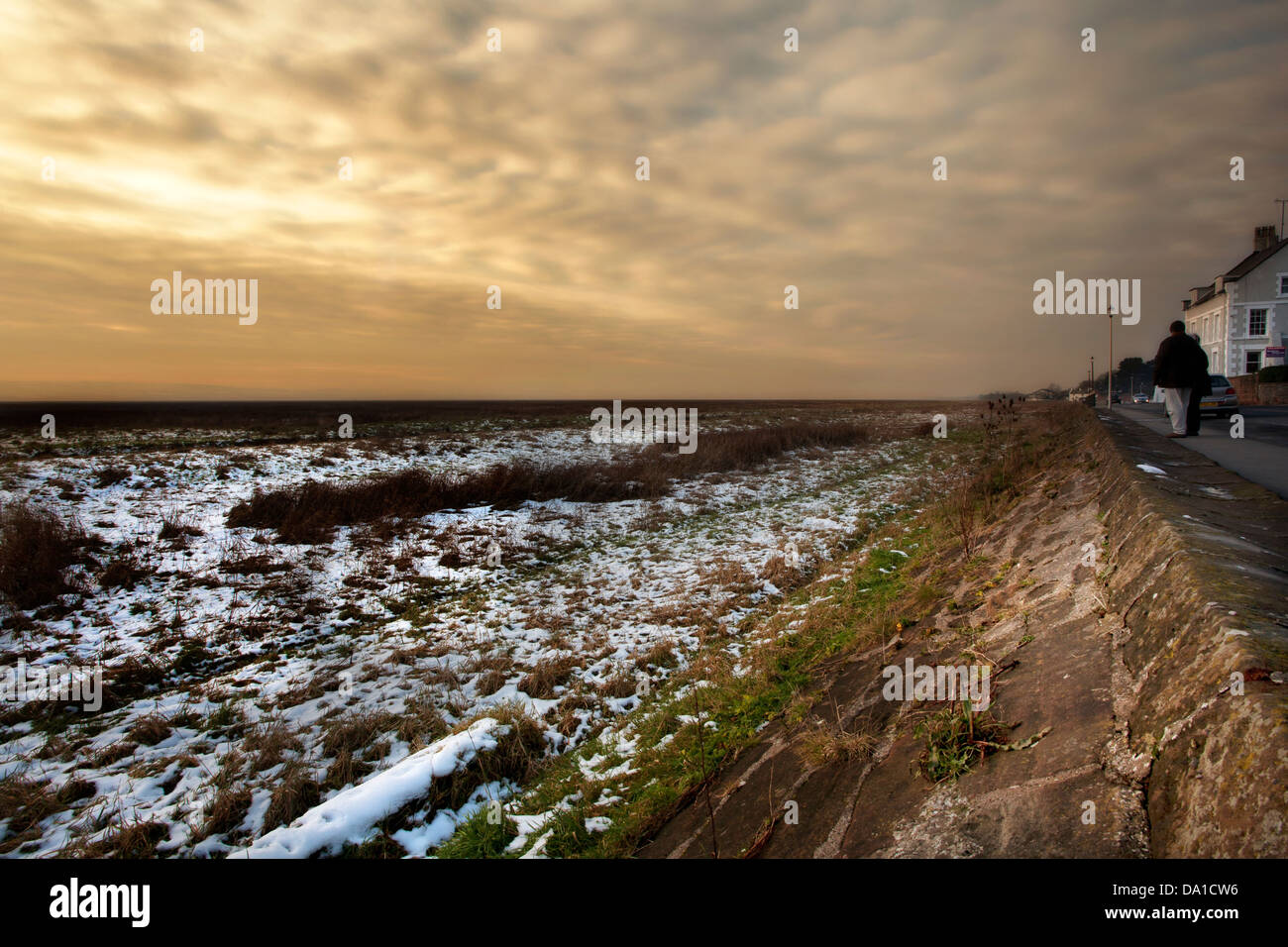 Impostazione di sun a Parkgate, Cheshire, mostrando le paludi con la neve e la parete del mare Foto Stock