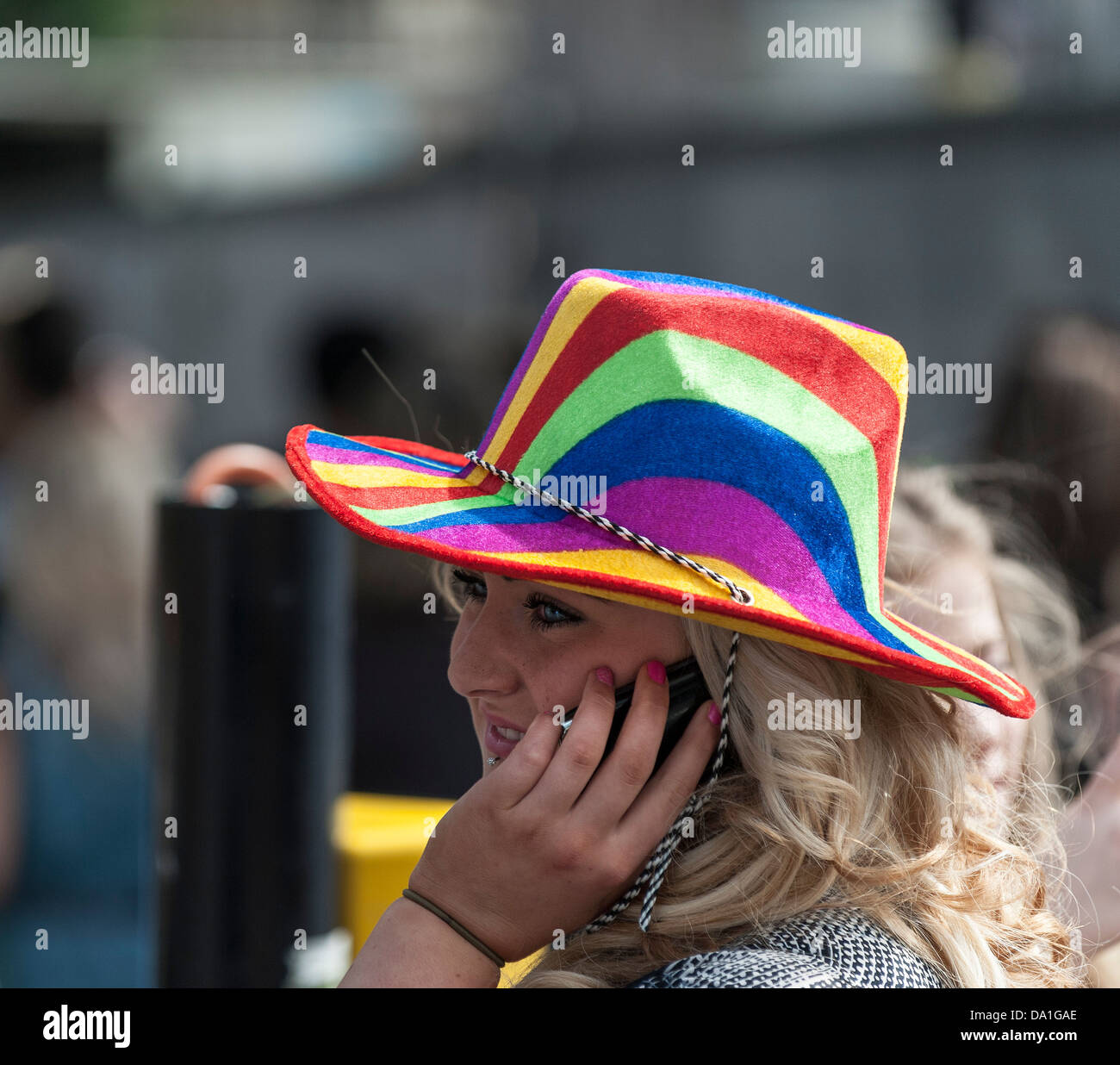 Una donna che indossa un cappello colorato a parlare su un telefono mobile durante il London Pride celebrazioni. Foto Stock
