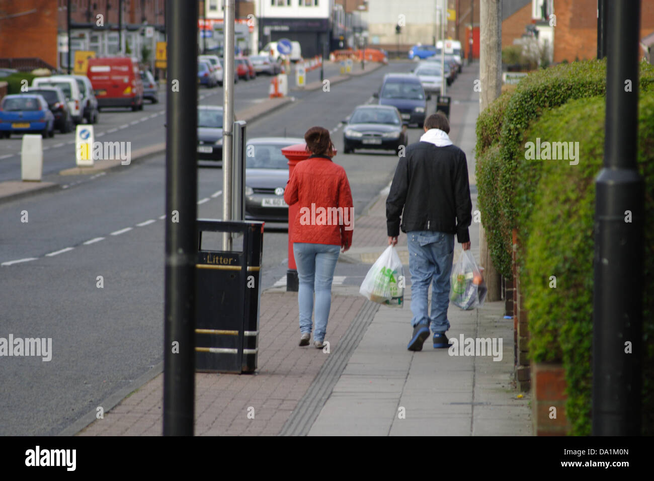 Un uomo e una donna a piedi giù per una strada. L uomo nella realizzazione dello shopping. Essi sono eventualmente un paio. Foto Stock