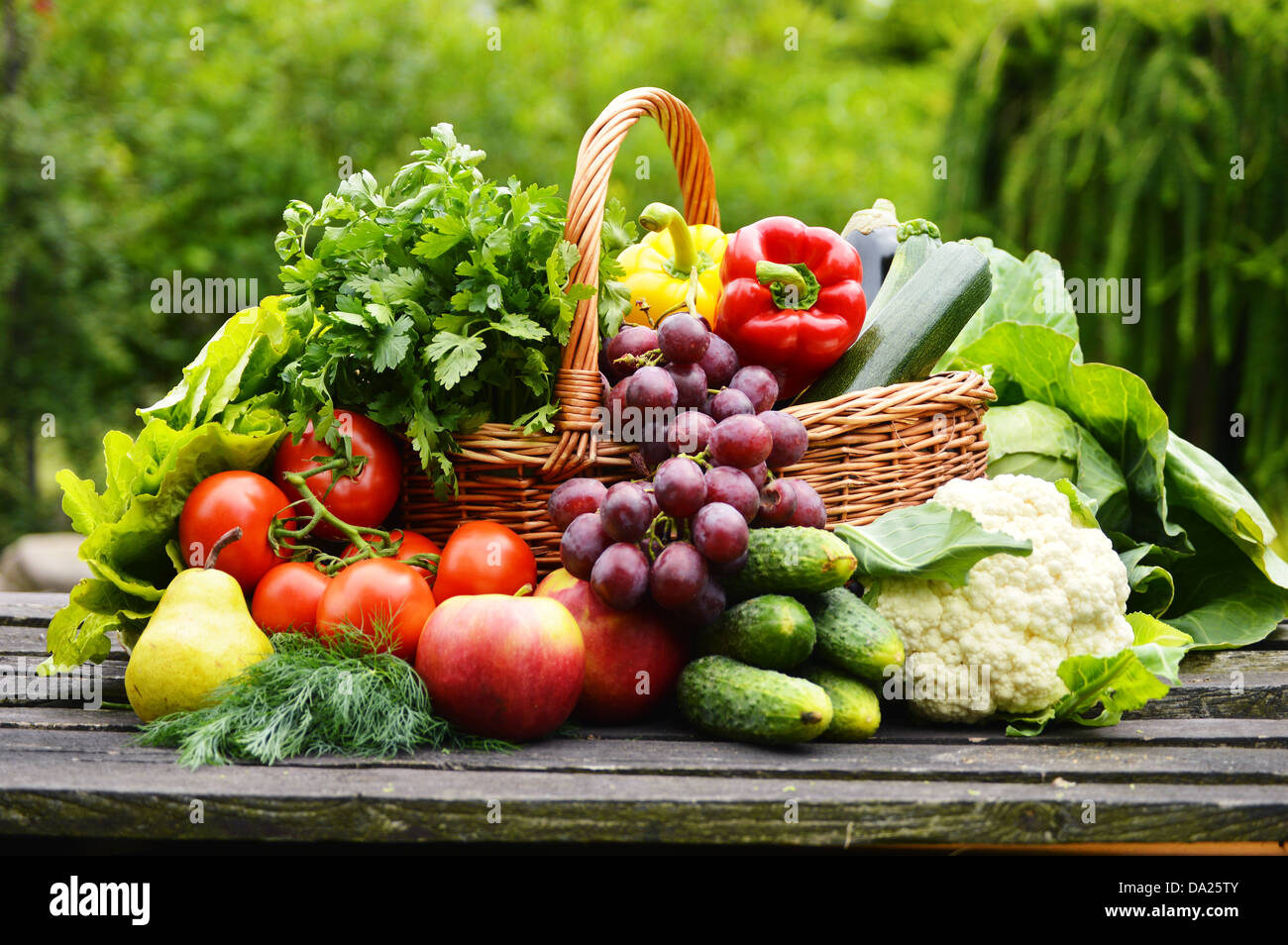 Fresche verdure organiche nel cesto di vimini in giardino Foto Stock