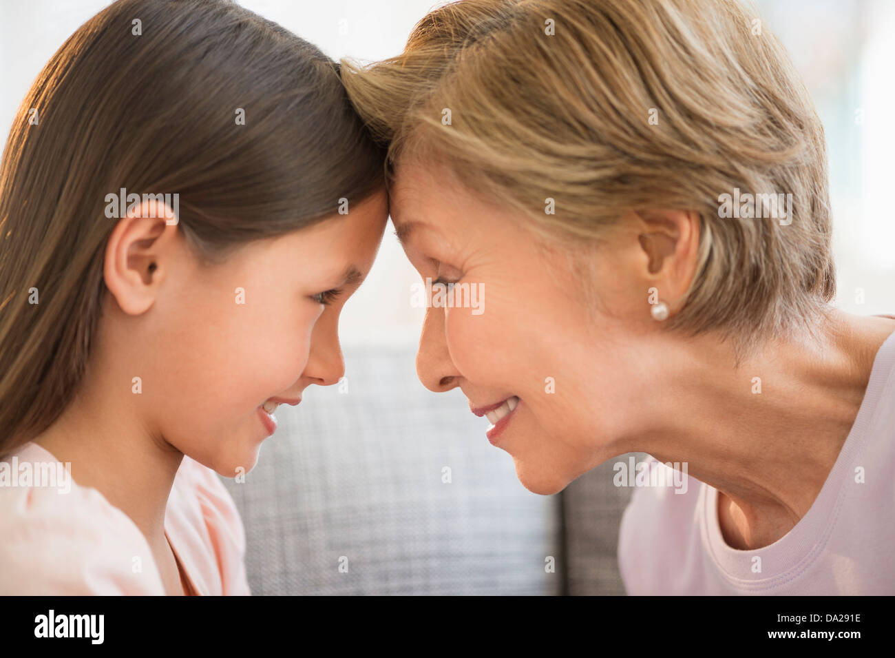 La nipote (8-9) e la nonna di toccare con teste Foto Stock