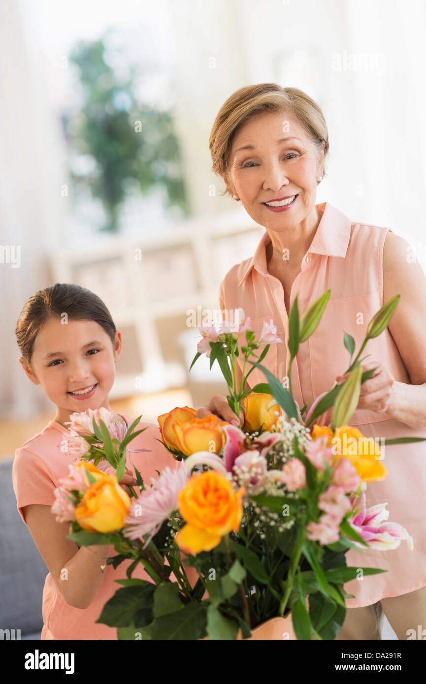 La nipote (8-9) e la nonna disponendo dei fiori a casa Foto Stock