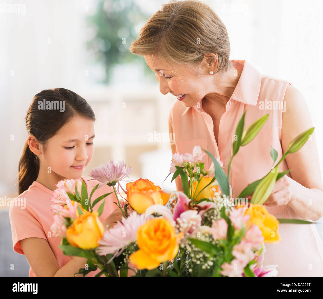 La nipote (8-9) e la nonna disponendo dei fiori a casa Foto Stock
