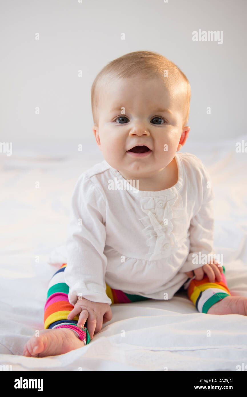 Ritratto di bambina (6-11 mesi) seduta nel letto Foto Stock