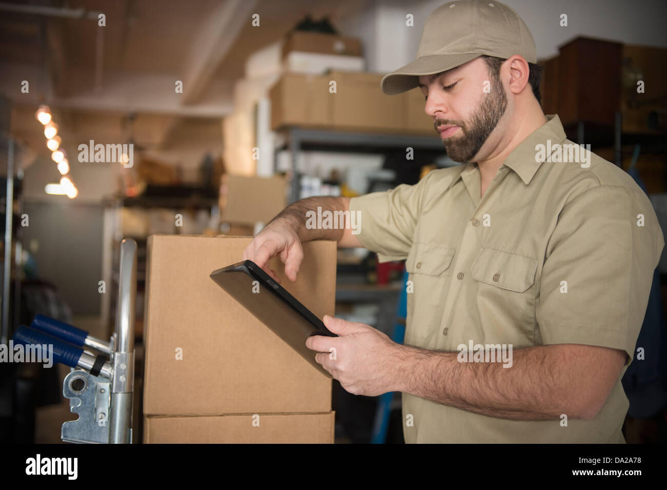 Uomo di consegna nel magazzino azienda portable informazioni dispositivo Foto Stock