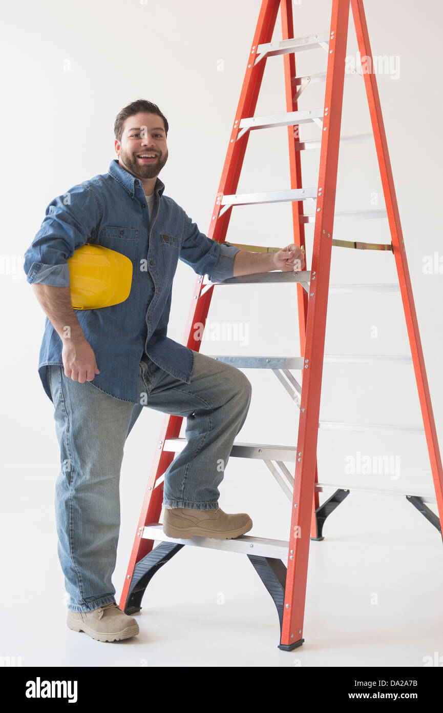 Ritratto di lavoratore edile in piedi dalla scaletta Foto Stock