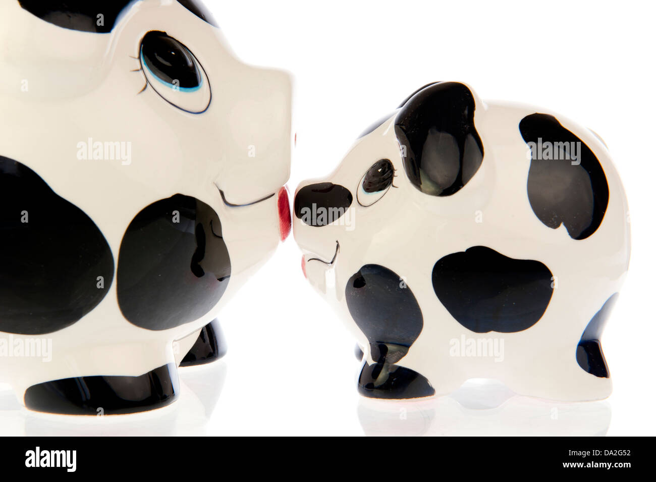 Due risparmiare denaro suini, la madre e il bambino in bianco e nero cow print, naso a naso kissing ogni altro Foto Stock