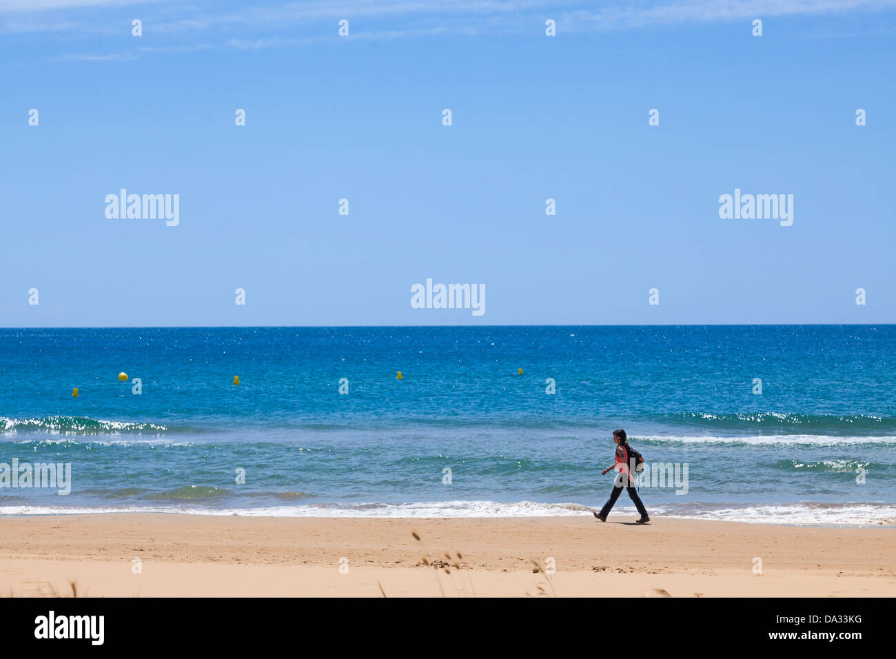 Una donna con zaino Camminare intenzionalmente alond beach dal mare Foto Stock