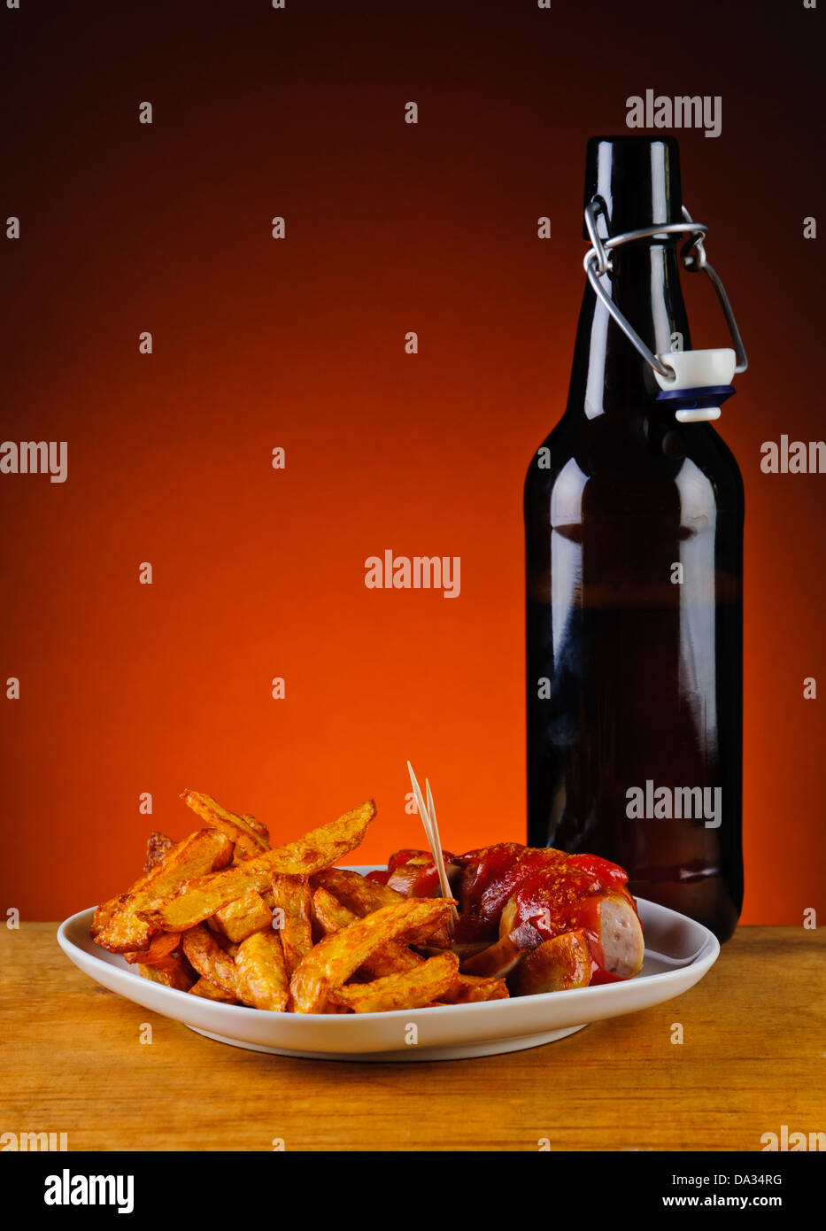 Salsiccia al curry con patatine fritte e una bottiglia di birra Foto Stock