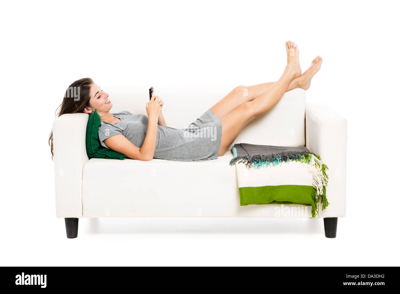 Bella donna su un divano con un cellulare sms, isolato in bianco Foto Stock