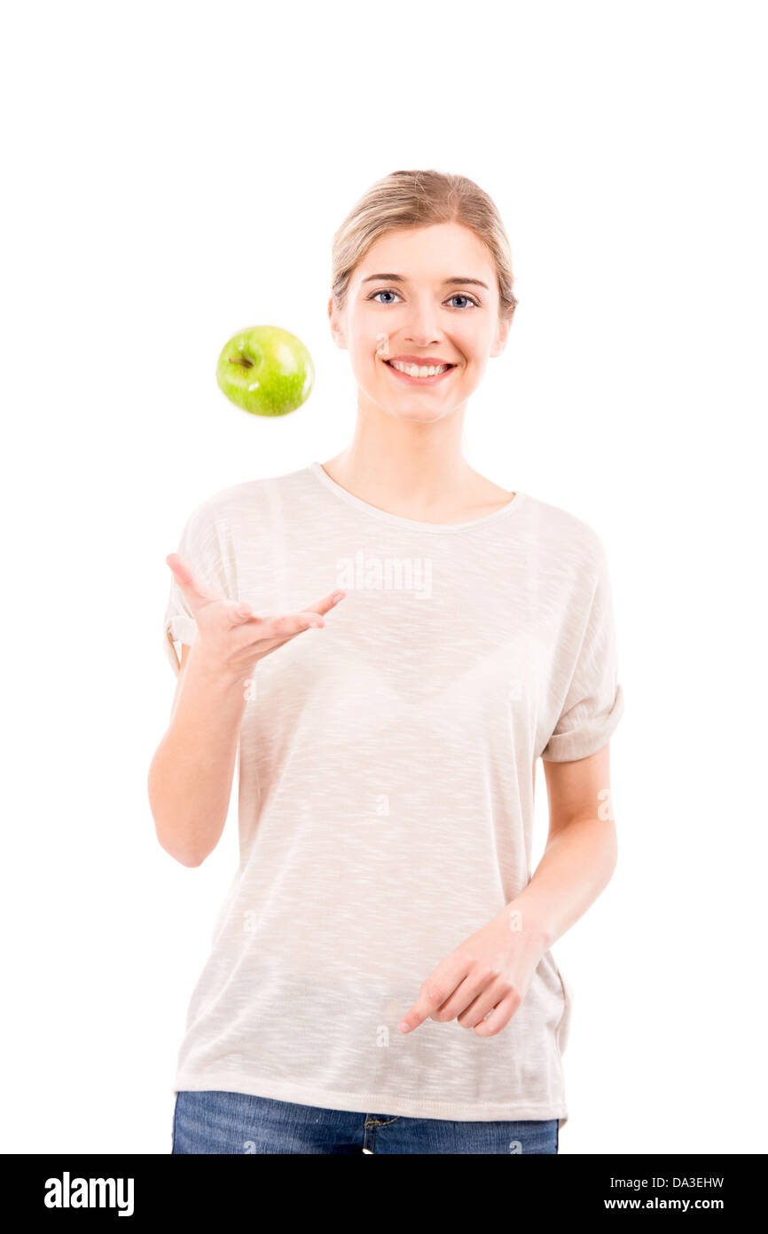 Bella ragazza gettando una mela verde in aria, su uno sfondo bianco Foto Stock