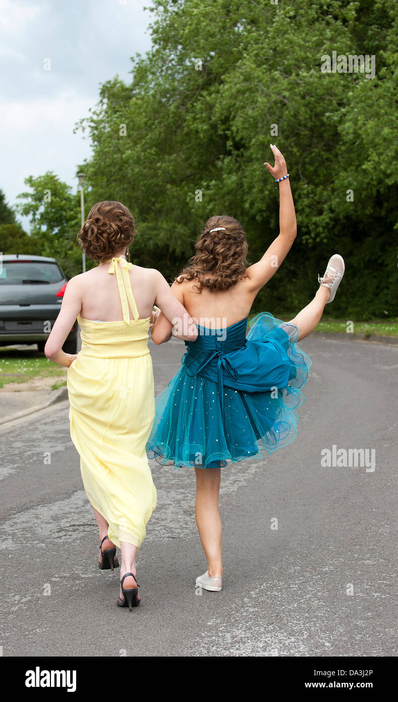 Le ragazze adolescenti in abiti a piedi lungo una strada, andando a parte alla fine del termine prom Foto Stock
