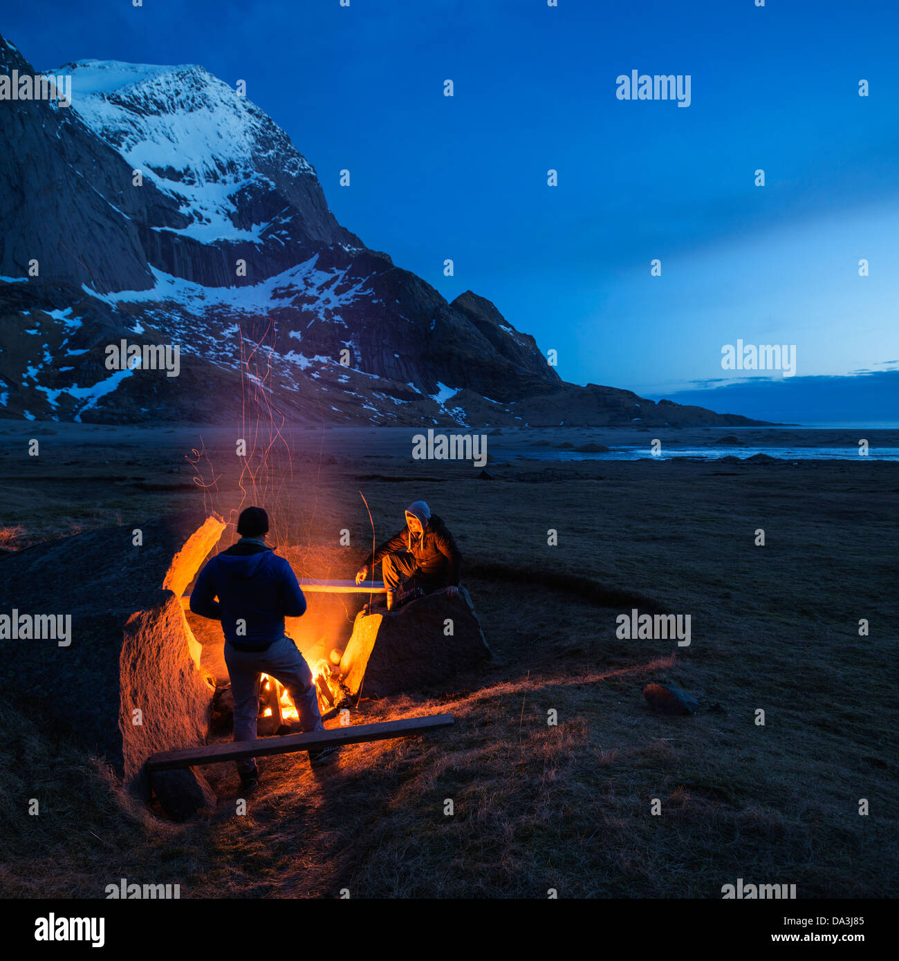 Due persone godono di falò in spiaggia Bunes, Moskenesoy, Isole Lofoten in Norvegia Foto Stock