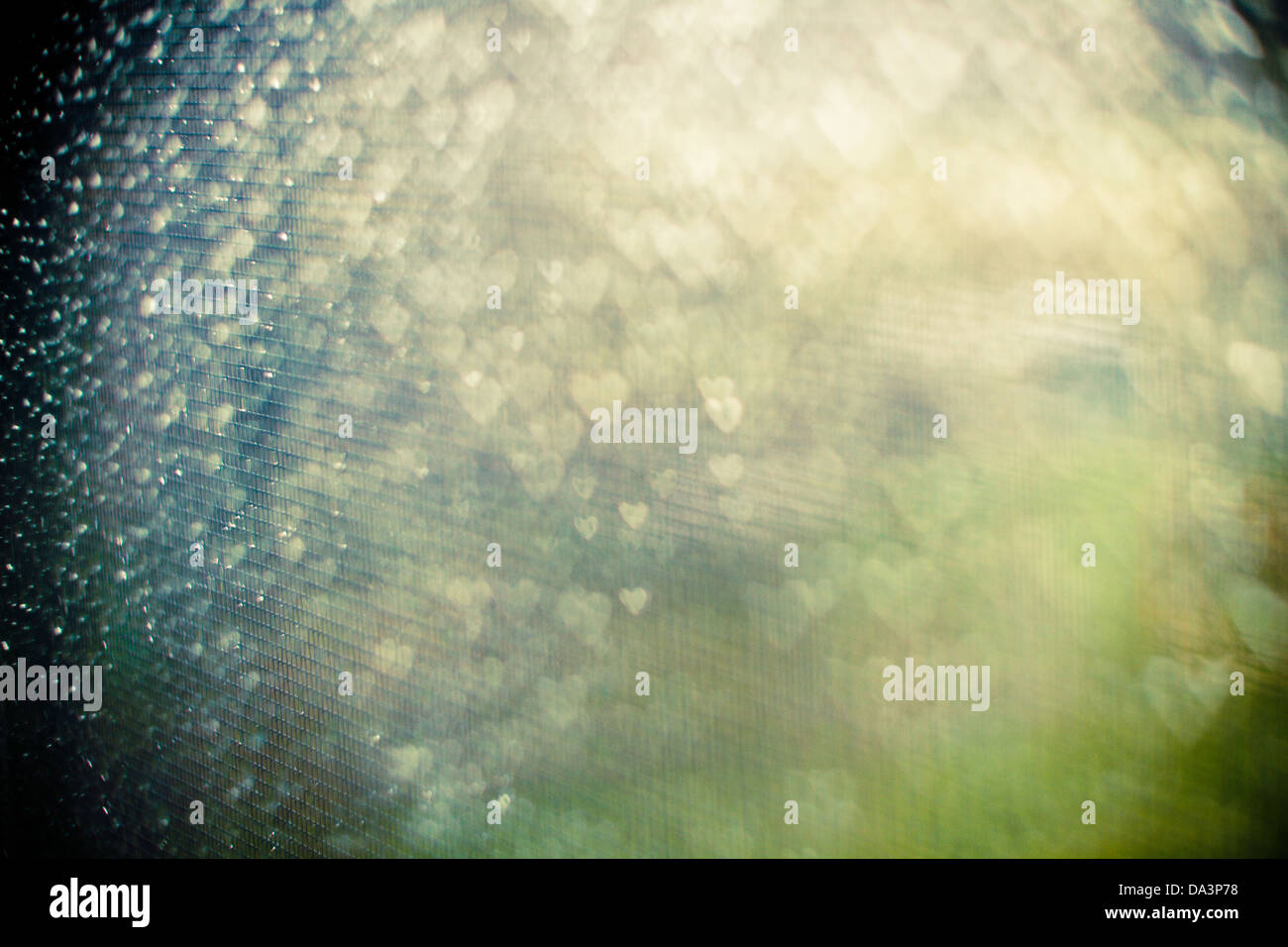 Pioggia-screziato finestra schermo punteggiato di bokeh cuori in verde, giallo e blu con toni forti la vignettatura Foto Stock