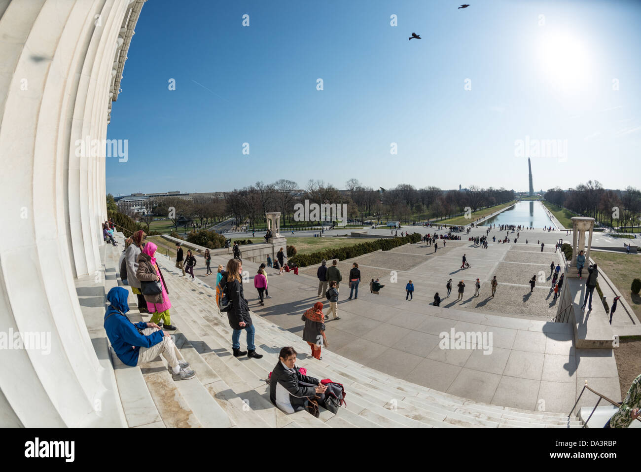 WASHINGTON DC, Stati Uniti d'America - i turisti sedersi sui gradini del Lincoln Memorial nella sun a Washington DC. In distanza a destra è il recentemente rinnovato che riflette la piscina e il Monumento a Washington in parte coperta da impalcature. Foto Stock