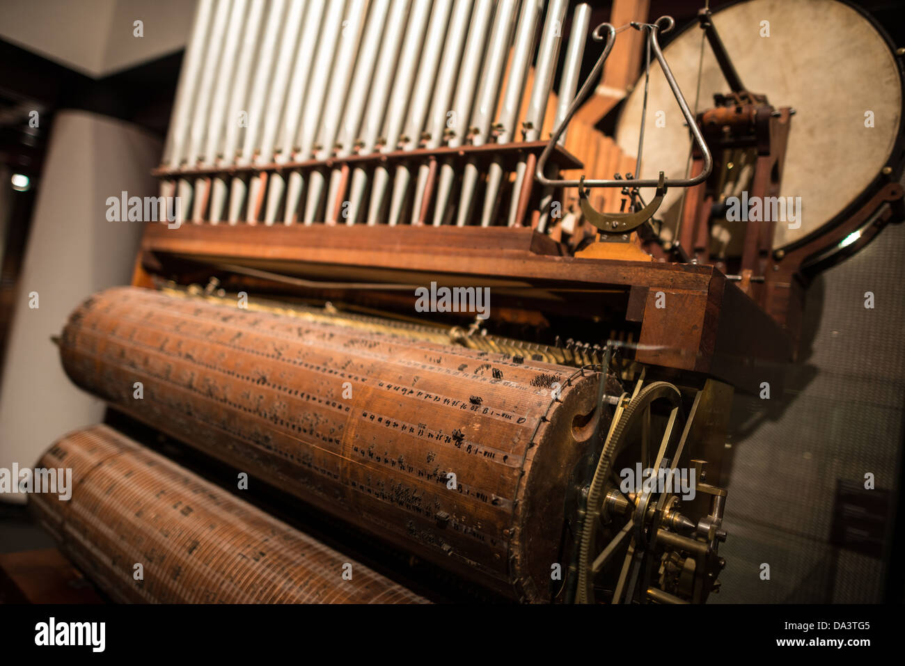 Museo degli Strumenti Musicali Pianola Organo a Canne Bruxelles Belgio | BRUSSELS, Belgio — Uno strumento ibrido automatizzato che combina elementi di organo a canne con percussioni meccaniche è esposto al Museo degli Strumenti Musicali. Il cilindro di legno prominente è costellato di perni metallici che funzionano come programmazione fisica: mentre il bariletto ruota, i perni attivano meccanicamente note specifiche e colpi di percussione. Questa tecnologia a barilletto-e-perno precede di secoli la bobina di carta perforata, rappresentando un ramo precedente dell'automazione analogica che ha anche azionato orologi musicali e organi da fiera. Il mu Foto Stock