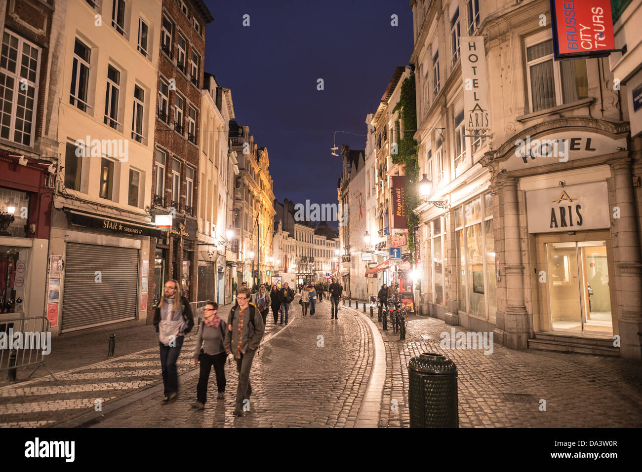 I turisti a piedi lungo una strada di ciottoli nella parte inferiore della città di Bruxelles, Belgio, di notte. Foto Stock