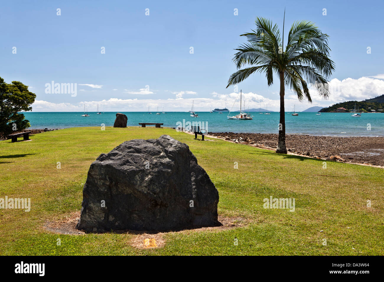 Un sasso o una pietra o boulder sta da solo, con un albero di palma a destra. Airlie Beach, Australia. Vicino alla Grande Barriera Corallina. Foto Stock