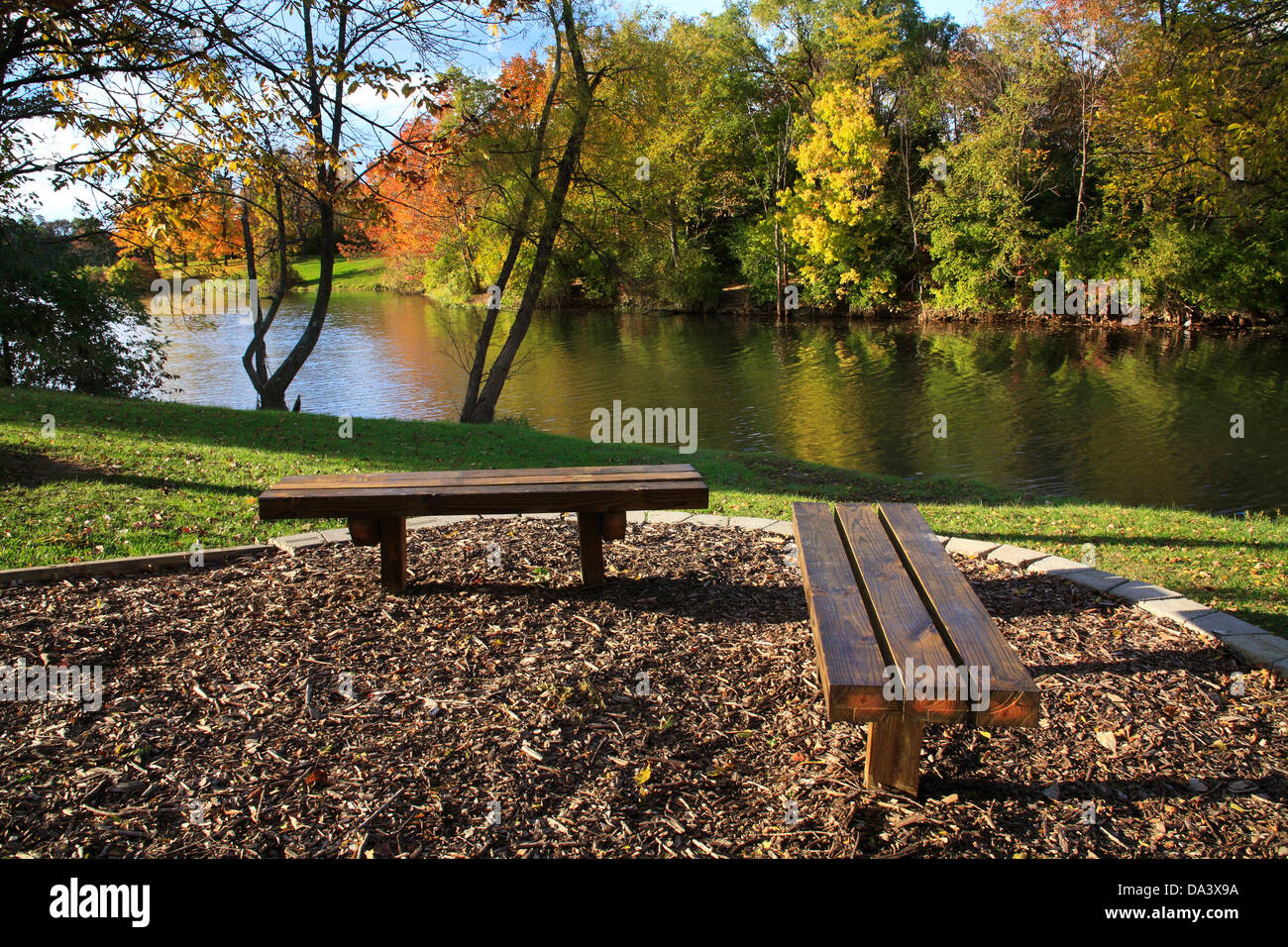 Legno panchine parco affacciato su un lago per la pesca sportiva in autunno, Southwestern Ohio, Stati Uniti d'America Foto Stock