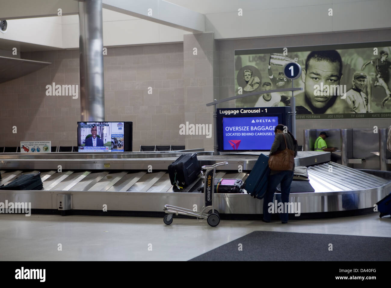 Una donna di ritirare il suo bagaglio presso il carosello bagagli di Detroit Metropolitan Wayne County Airport' MacNamara terminale Foto Stock