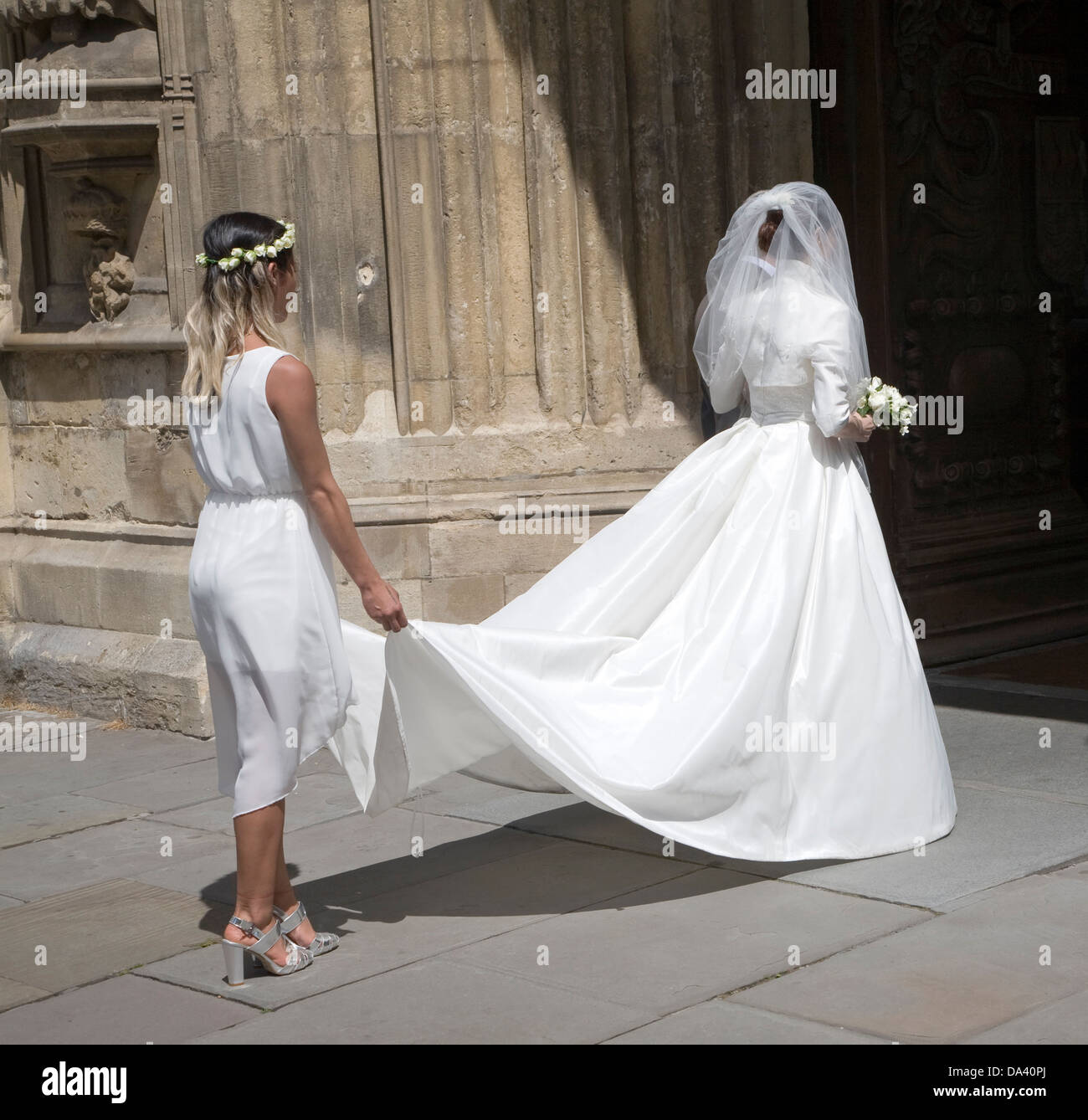 Sposa in abito bianco e la damigella entrando in chiesa, Abbazia di Bath Somerset, Inghilterra Foto Stock
